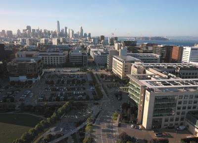 Aerial view of UCSF's Mission Bay campus with the San Francisco skyline visible in the background.